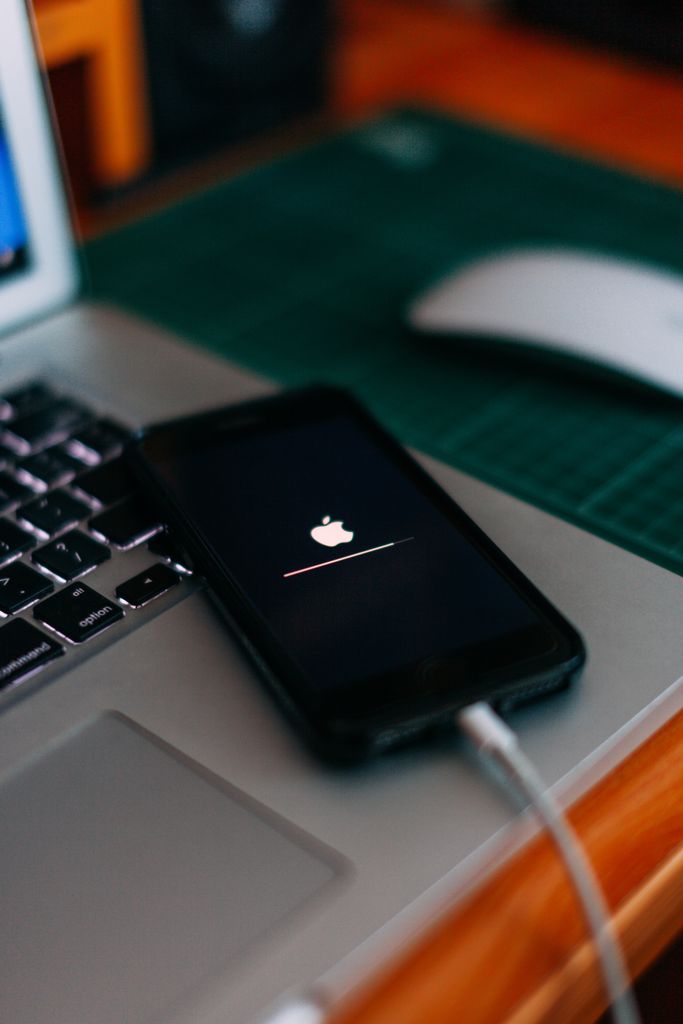 Close-up of a smartphone charging on a laptop. Ideal for tech themes.